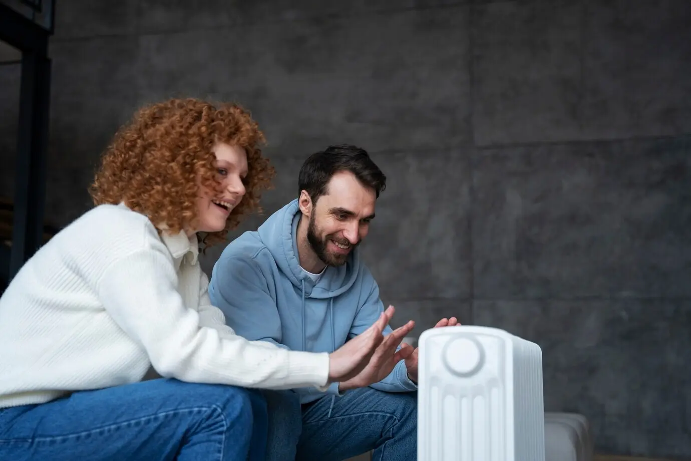 Medium shot of a couple warming themselves with a heater.