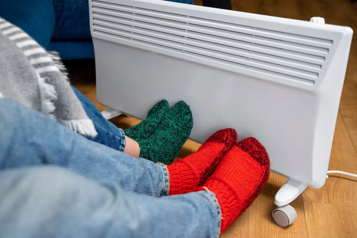 Close-up of people’s legs near a heater.
